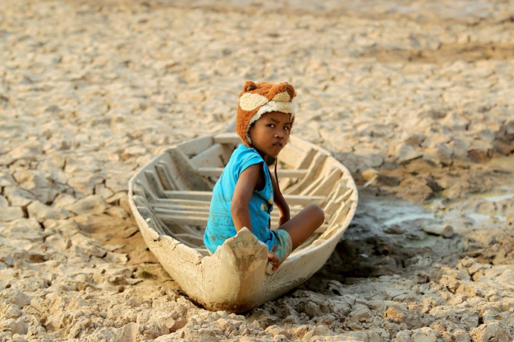 a-girl-sits-on-a-boat-at-a-dried-up-pond-at-the-drought-hit-kandal-province-in-cambodia-on-may-13