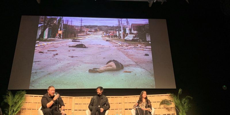 Un moment de la xerrada amb una fotografia, al darrere dels ponents, de Bucha feta per Palacios. Foto: Laia Micó